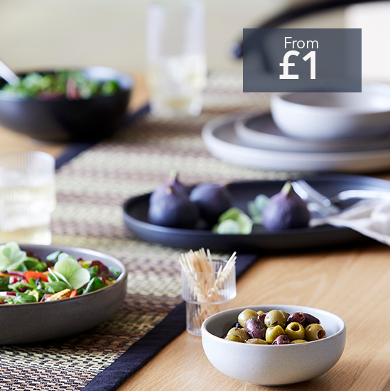 stoneware dining pieces on a light wood table with olives, salad and figs